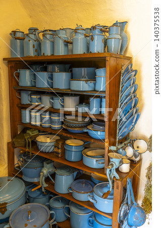 Vintage blue enamel kitchenware collection on wooden shelves 140375538