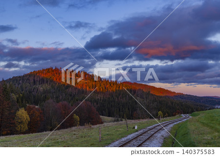 Train track curving through forest mountains at Oravska Lesna sunset Train track curving through forest mountains at Oravska Lesna sunset 140375583