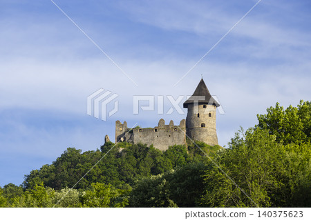 Salgo Castle ruins standing on forested hill under blue sky Salgo Castle ruins standing on forested hill under blue sky 140375623