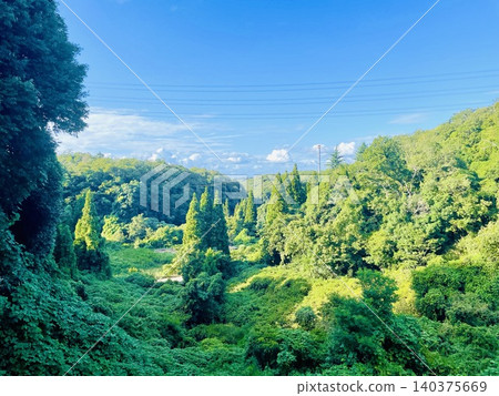 A beautiful landscape with a blue sky and lush green mountains. 140375669