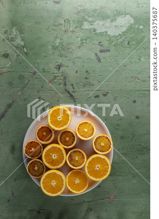Citrus fruit halves on plate against green background Citrus fruit halves on plate against green background 140375687
