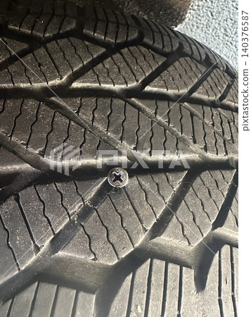 一顆金屬螺絲扎進了汽車輪胎——輪胎被刺破的畫面。 140376587