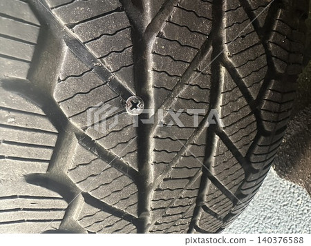 一張汽車輪胎被螺絲刺破的特寫照片。 140376588
