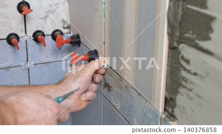Worker Laying Ceramic Tiles on the Wall. Repairman Placing White Gray Square Tiles, Applying Adhesive. Builder Installing Tile Using Leveler, Tile Leveling Clips. Tiling. Finishing Repair Work. 4K Worker Laying Ceramic Tiles on the Wall. Repairman Placing White Gray Square Tiles, Applying Adhesive. Builder Installing Tile Using Leveler, Tile Leveling Clips. Tiling. Finishing Repair Work. 4K 140376858