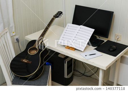 Equipment for recording music in the home studio, guitar, headphones, laptop. Leisure, music and people concept. Workspace with laptop and acoustic guitar on wooden table. Musician online learning Equipment for recording music in the home studio, guitar, headphones, laptop. Leisure, music and people concept. Workspace with laptop and acoustic guitar on wooden table. Musician online learning 140377118