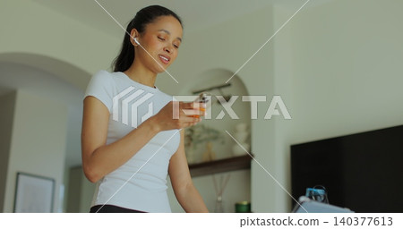 Sporty young american female in training clothes doing stepping exercises on running track and uses her smartphone. 140377613