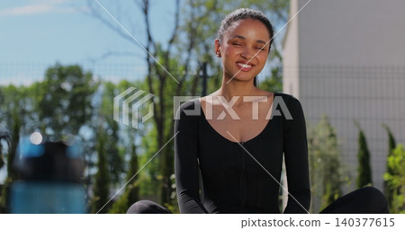 Portrait of a sporty woman resting after training in backyard. Beautiful healthy sportive girl athlete resting after intense hard training. Portrait of a sporty woman resting after training in backyard. Beautiful healthy sportive girl athlete resting after intense hard training. 140377615
