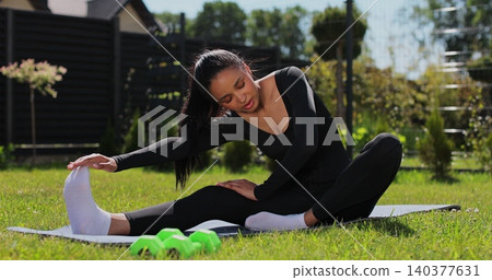 Fit girl in sportswear exercising. Outdoor training workout for muscle strength. Athletic woman doing training outdoors. Fit girl in sportswear exercising. Outdoor training workout for muscle strength. Athletic woman doing training outdoors. 140377631