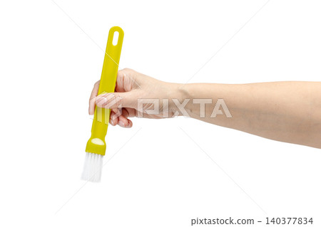 Woman's hand holding a cooking brush on the white background. Woman's hand holding a cooking brush on the white background. 140377834