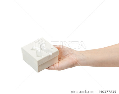 Woman's hand holding a gift box on her palm with the white background. Woman's hand holding a gift box on her palm with the white background. 140377835