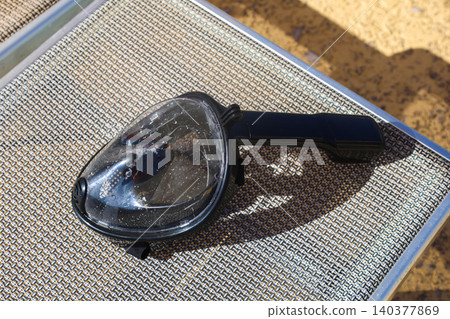 Snorkeling mask resting on the mesh of a sun lounger at a tropical beach resort Snorkeling mask resting on the mesh of a sun lounger at a tropical beach resort 140377869