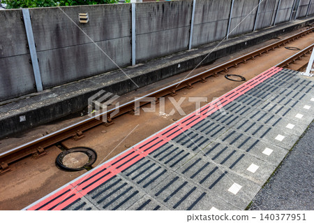 從高處俯瞰車站月台和軌道,包括板式軌道和盲道。 從高處俯瞰車站月台和軌道,包括板式軌道和盲道。 140377951