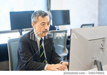 辦公室裡,資深商務人士正專注於電腦工作。 辦公室裡,資深商務人士正專注於電腦工作。 140378002