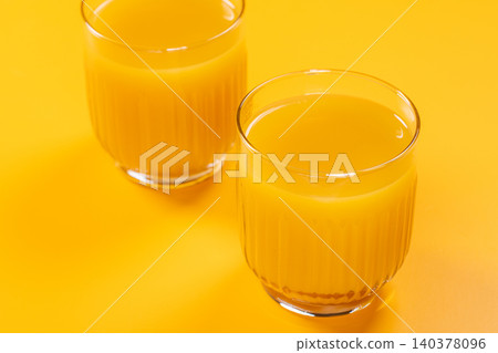 Two glasses of fresh orange juice on yellow background Two glasses of fresh orange juice on yellow background 140378096