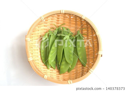 Snow peas arranged on a sieve against a white background. Snow peas arranged on a sieve against a white background. 140378373