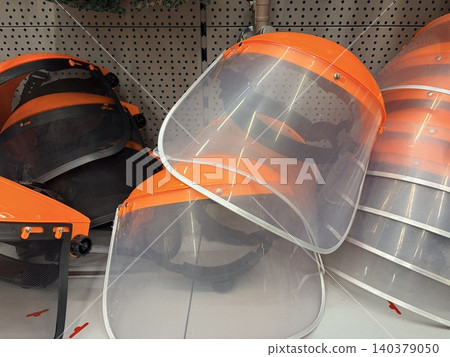 Several protective face shields arranged on a retail store shelf. A hardware or safety equipment store setting Several protective face shields arranged on a retail store shelf. A hardware or safety equipment store setting 140379050