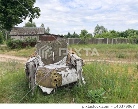 a heavily decayed and abandoned armchair sitting alone in an overgrown grassy field. a heavily decayed and abandoned armchair sitting alone in an overgrown grassy field. 140379067