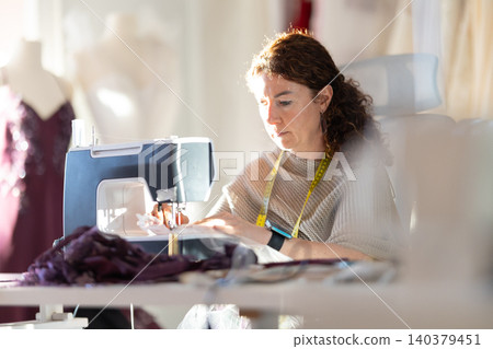 Sewing in a studio during daylight while focusing on fabric and patterns Sewing in a studio during daylight while focusing on fabric and patterns 140379451