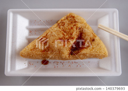 A bird's-eye view of a triangular fried tofu – a fragrant piece topped with shichimi spice and soy sauce. 140379693