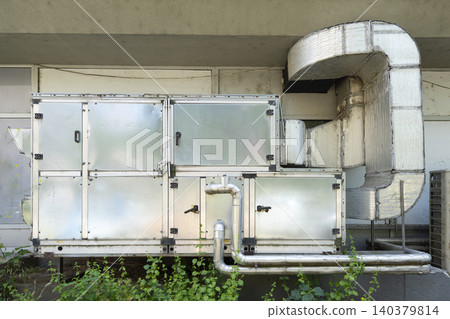An industrial air conditioning unit is shown mounted on a building exterior. An industrial air conditioning unit is shown mounted on a building exterior. 140379814