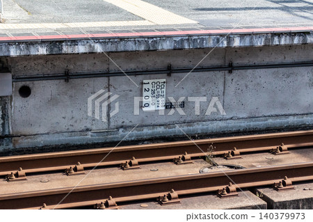 Railway curve markers and platform underwall; close-up of slab track and rails (oblique overhead view) Railway curve markers and platform underwall; close-up of slab track and rails (oblique overhead view) 140379973