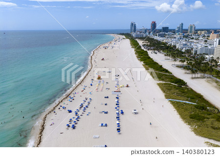 Drone aerial view of Miami sandy beach. Wide drone shot of Miami Beach and ocean waves. Miami beachscape captured from above. Drone aerial view of Miami sandy beach. Wide drone shot of Miami Beach and ocean waves. Miami beachscape captured from above. 140380123