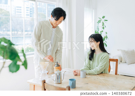 一個男人在磨咖啡豆，一個女人在一旁看著。 140380672