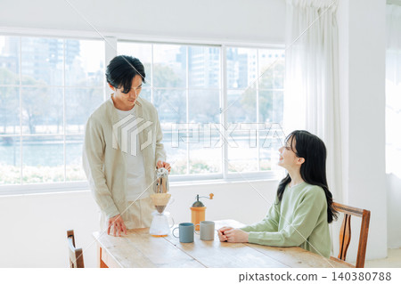 A man brewing coffee and a woman watching him. A man brewing coffee and a woman watching him. 140380788