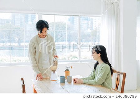 一個男人在煮咖啡，一個女人在看他。 140380789