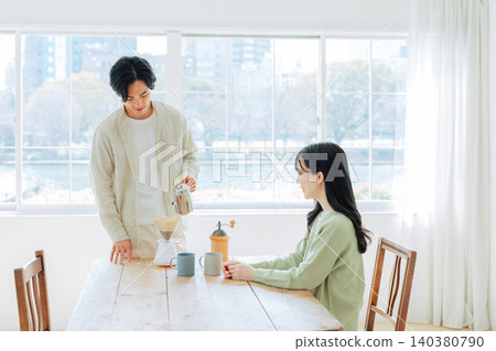 A man brewing coffee and a woman watching him. 140380790