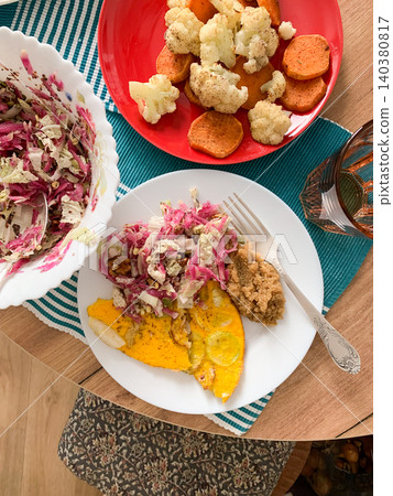 A nutritious meal featuring amaranth porridge, zucchini omelette, fresh salad, and baked cauliflower and sweet potato arranged on a table with simple decor A nutritious meal featuring amaranth porridge, zucchini omelette, fresh salad, and baked cauliflower and sweet potato arranged on a table with simple decor 140380817