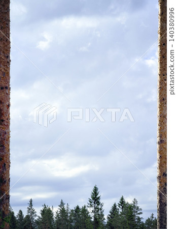 Cloudy sky framed by rough stone edges above a tree line Cloudy sky framed by rough stone edges above a tree line 140380996