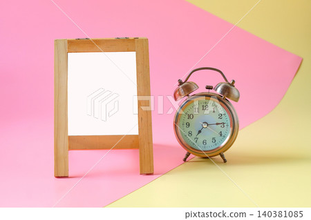 wooden easel with alarm clock on two tone background. 140381085