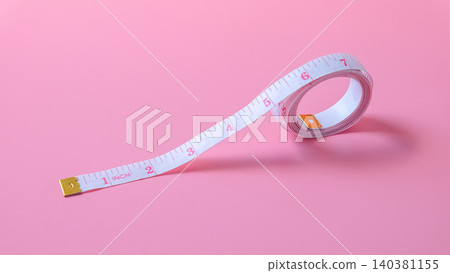 A white measuring tape on pink background. A white measuring tape on pink background. 140381155