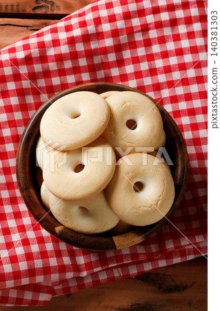 Traditional Cassava Starch Biscuits in Bowl on Red Checkered Fabric, Rustic Wooden Table Background Traditional Cassava Starch Biscuits in Bowl on Red Checkered Fabric, Rustic Wooden Table Background 140381303