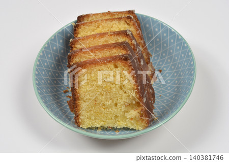 Slices of glazed lemon pound cake in a blue bowl 140381746