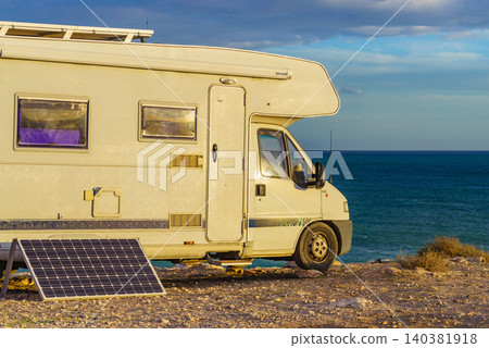 Camper with portable glass solar panel camping on sea shore Camper with portable glass solar panel camping on sea shore 140381918