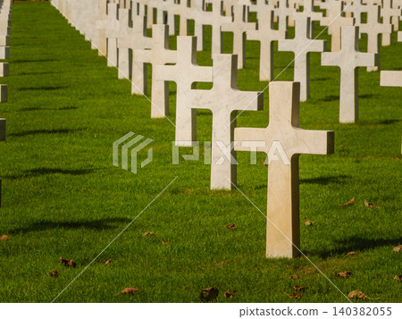 Graves with white crosses arranged in rows on green grass in a memorial cemetery during daylight hours Graves with white crosses arranged in rows on green grass in a memorial cemetery during daylight hours 140382055