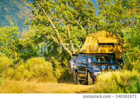 Camping setup with rooftop tent on vehicle in a natural setting Camping setup with rooftop tent on vehicle in a natural setting 140382071
