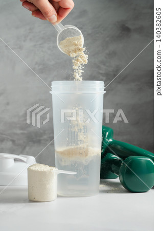 Protein powder falling into shaker bottle during fitness drink preparation Protein powder falling into shaker bottle during fitness drink preparation 140382605