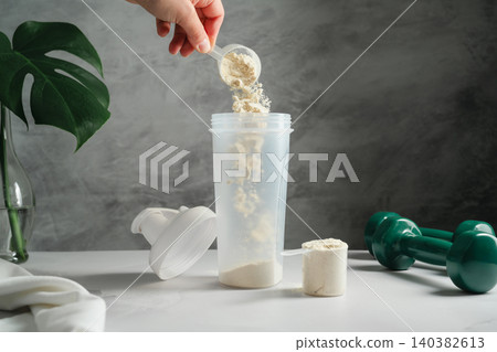 Scoop of protein powder poured into shaker for muscle recovery drink Scoop of protein powder poured into shaker for muscle recovery drink 140382613