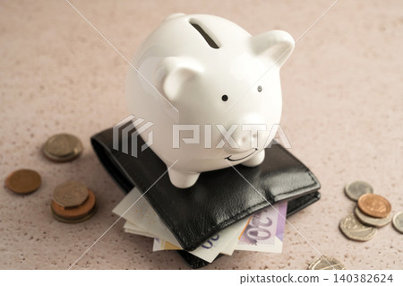 Piggy bank on wallet with cash and coins, savings personal finance wealth management and budgeting concept Piggy bank on wallet with cash and coins, savings personal finance wealth management and budgeting concept 140382624