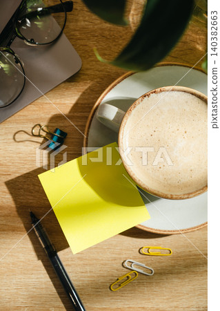 Coffee cup with blank sticky note on office desk, top view workspace mockup with copy space 140382663