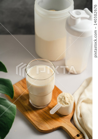 Protein shake glass with sports nutrition supplement and scoop Protein shake glass with sports nutrition supplement and scoop 140382676