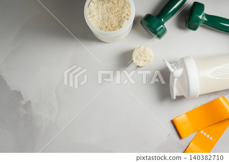 Protein shake and fitness equipment on gray background, sports nutrition flat lay 140382710