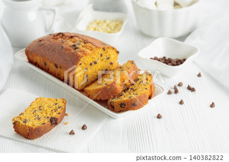 Cake with chocolate pieces on a white table. Cake with chocolate pieces on a white table. 140382822