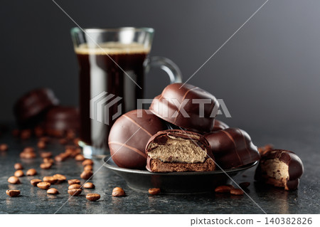 Chocolate-covered coffee souffle cookies and cup of black coffee. Chocolate-covered coffee souffle cookies and cup of black coffee. 140382826