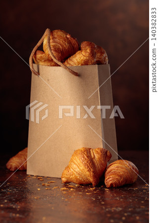 Fresh croissants in paper bag on a brown vintage table. Fresh croissants in paper bag on a brown vintage table. 140382833