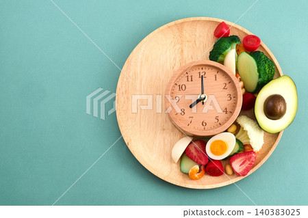 Wooden clock with healthy fresh food for intermittent fasting 140383025