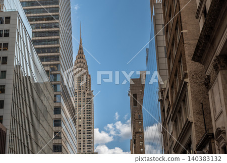 New york, usa august 22,2024. Chrysler building crown and spire prominently rising above other skyscrapers, showcasing iconic art deco design in midtown manhattan New york, usa august 22,2024. Chrysler building crown and spire prominently rising above other skyscrapers, showcasing iconic art deco design in midtown manhattan 140383132